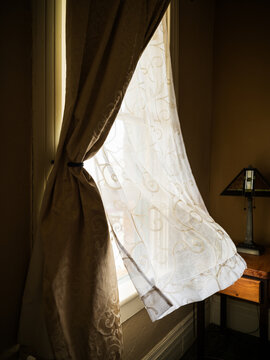 Wind blows into the open window of a vintage hotel room