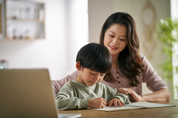 young asian mother helping son with homework