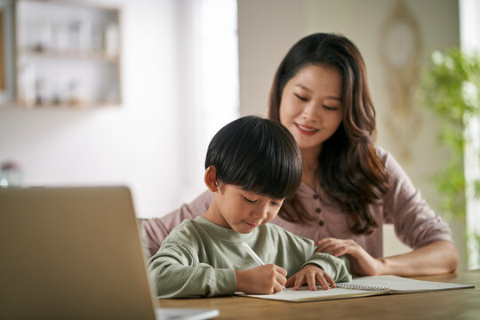 young asian mother helping son with homework