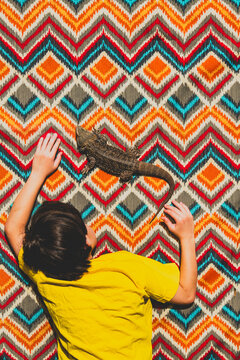 A boy and his bearded dragon lie on a brightly patterned blanket in the sun, seen from above