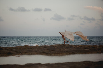 bailarin danzando con tela voladora en la playa