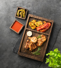 BBQ grilled pork fillet medallions with pepper, zucchini, rosemary and sauce on a wooden board on a dark background with fresh herb and snack. The concept of a delicious healthy dinner with meat.