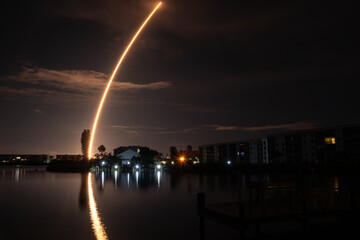Fototapeta na wymiar Reflections of Nighttime Rocket Launch over The Water 