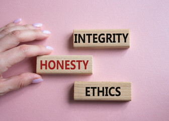 Integrity Honesty Ethics symbol. Concept words Integrity Honesty Ethics on wooden blocks. Businessman hand. Beautiful pink background. Business and Integrity Honesty Ethics concept. Copy space.