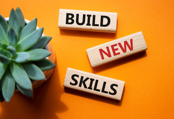 Build New skills symbol. Concept word Build New skills on wooden blocks. Beautiful orange...
