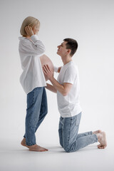 Family couple. A pregnant blond woman of Caucasian appearance is having sex with her husband, they look at each other and gently touch their stomachs. They wear jeans and a white T-shirt.