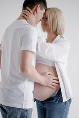 Family couple. A pregnant blond woman of Caucasian appearance is having sex with her husband, they look at each other and gently touch their stomachs. They wear jeans and a white T-shirt.