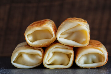Stack of fried pancakes, closeup. Traditional Ukrainian pancakes stuffed with meat filling. Homemade baking. Delicious fast food for breakfast