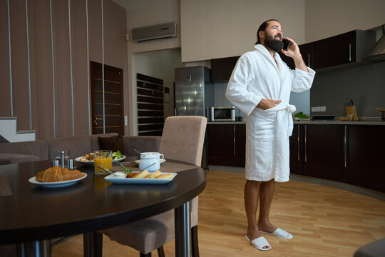 Bearded male in a bathrobe communicates on a mobile phone