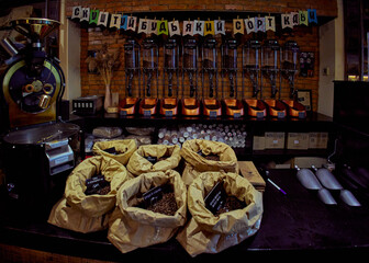 Bags with different types of coffee on a table in a coffee shop. You can try any kind of coffee written on the poster.