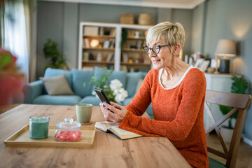 one mature senior caucasian woman use mobile phone smartphone at home