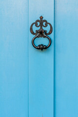 niebieskie drewniane drzwi z czarną kołatką - obrazy, fototapety, plakaty