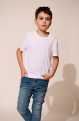 Authentic Hispanic teenage boy in white t-shirt and blue jeans, putting his hands in pockets, thoughtfully looking away
