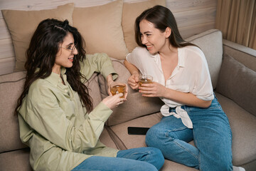 Two pretty ladies talking while sitting on couch