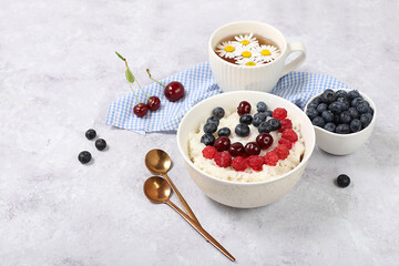 Healthy breakfast with ingredients, milk rice porridge with fresh blueberries, cherries and raspberries, creamy rice pudding or French rice with honey and chamomile tea. Natural nutrition concept