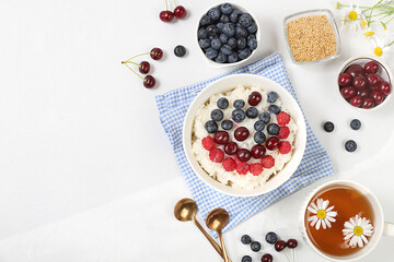 Healthy breakfast with ingredients, milk rice porridge with fresh blueberries, cherries and raspberries, creamy rice pudding with flax seeds and chamomile tea. Natural nutrition 