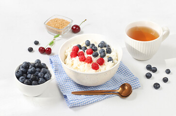Healthy breakfast with ingredients, milk rice porridge with fresh blueberries, cherries and raspberries, creamy rice pudding with flax seeds and chamomile tea. Natural nutrition 