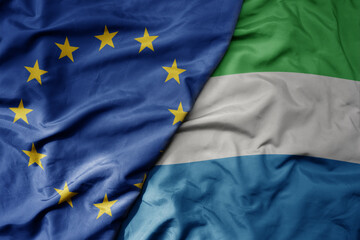 big waving realistic national colorful flag of european union and national flag of sierra leone .