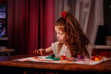 Cute little girl painting with fingers at home. Creative games for kids. Stay at home entertainment