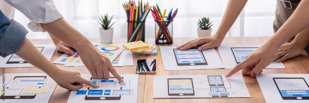 Poster Panorama shot of front-end developer team brainstorming UI and UX designs for mobile app on paper wireframe interface. User interface development team planning for user-friendly UI design. Scrutinize