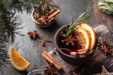 Mulled wine in ceramic mug with spices. Christmas hot drink on wooden table with xmas tree branches