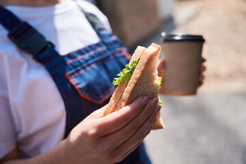 Building engineer has lunch break, eating sandwich and drinking coffee