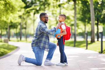Father escorts happy first-grader boy to school, straightens his bow tie