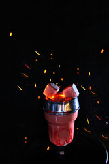 Hot coals for hookah smoking and relaxation. Dark background, smoke, sparks.Copy space.Vertical photo.