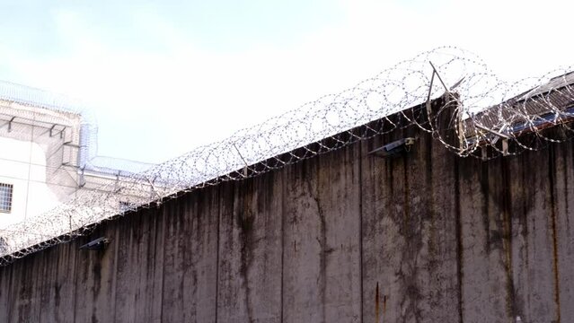 high concrete fence, barbed wire fence on top, pre-trial detention cell, building for execution of punishments for criminals, concept prison, security zone, hopelessness of captivity