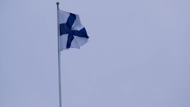 silk national flag of European state of Finland flutters in the wind in the blue sky, concept of tourism, economy, politics, independence day, rights and freedoms of citizens, fair elections