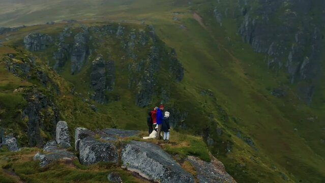 Young Family With Two Kids And A White Dog Standing On The Top Of A Fjord. Drone Flies Around.