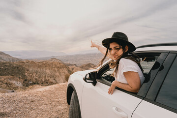 Naklejka premium Female traveler going out of the car window to appreciate the landscape