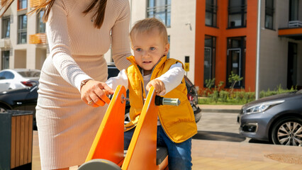 Cute baby boy riding on the bouncy spring rider on the the playground at amusement park. Children playing outdoor, kids outside, summer holiday and vacation.