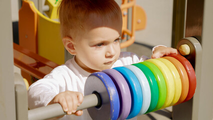 Portrait of baby boy playing on the wooden playground. Children developments, kids education, baby learning.