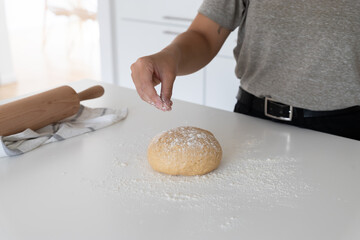 young woman placing flour to homemade dough