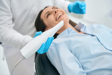 Fototapeta premium Stomatologist in uniform taking intraoral camera to examine mouth inside