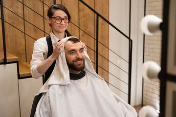 Barber dries the hair of the client with soft towel