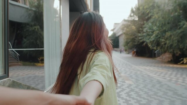Relaxed girl holding boyfriend hand leading in city center closeup. Cheerful couple walking in city enjoying beautiful town view. Smiling woman have fun outdoors. Follow me concept