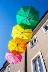 Four colorful umbrellas hangling over the street of Villach, Austria- red, orange, yellow and green