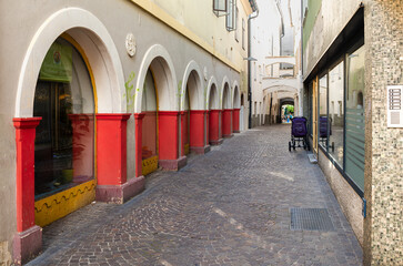 Fototapeta na wymiar Villach, Austria - July 12, 2023: A street with arcades, partly red, in the old town of Villach