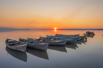 boats standing still in the lake with reflection at sunset