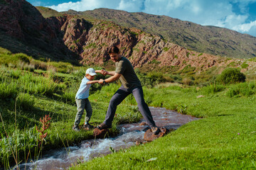 Father helps his son cross mountains stream