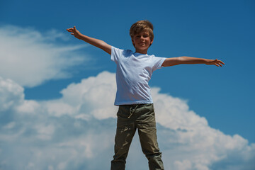 Happy boy standing on sky background enjoying freedom