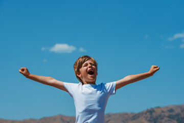 Happy boy yawn and stretch hands on mountains background