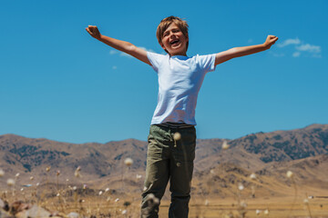 Happy boy tourist stretching hands on mountains background