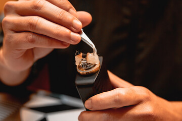The technician using tweezers to separate the cotton from the vape.