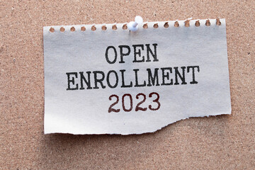 OPEN ENROLLMENT 2023. Text on green business card with pen