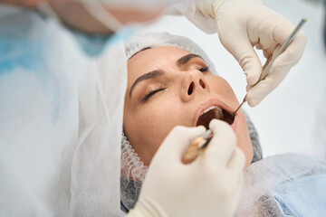 Doctor in modern dental clinic cleans dental canals of young woman