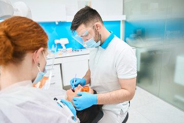 Doctor in a dental office puts photopolymer filling on patient