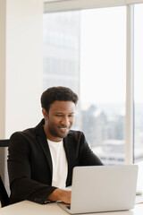 Smiling african american employee, using laptop, computer, freelancer working in modern office